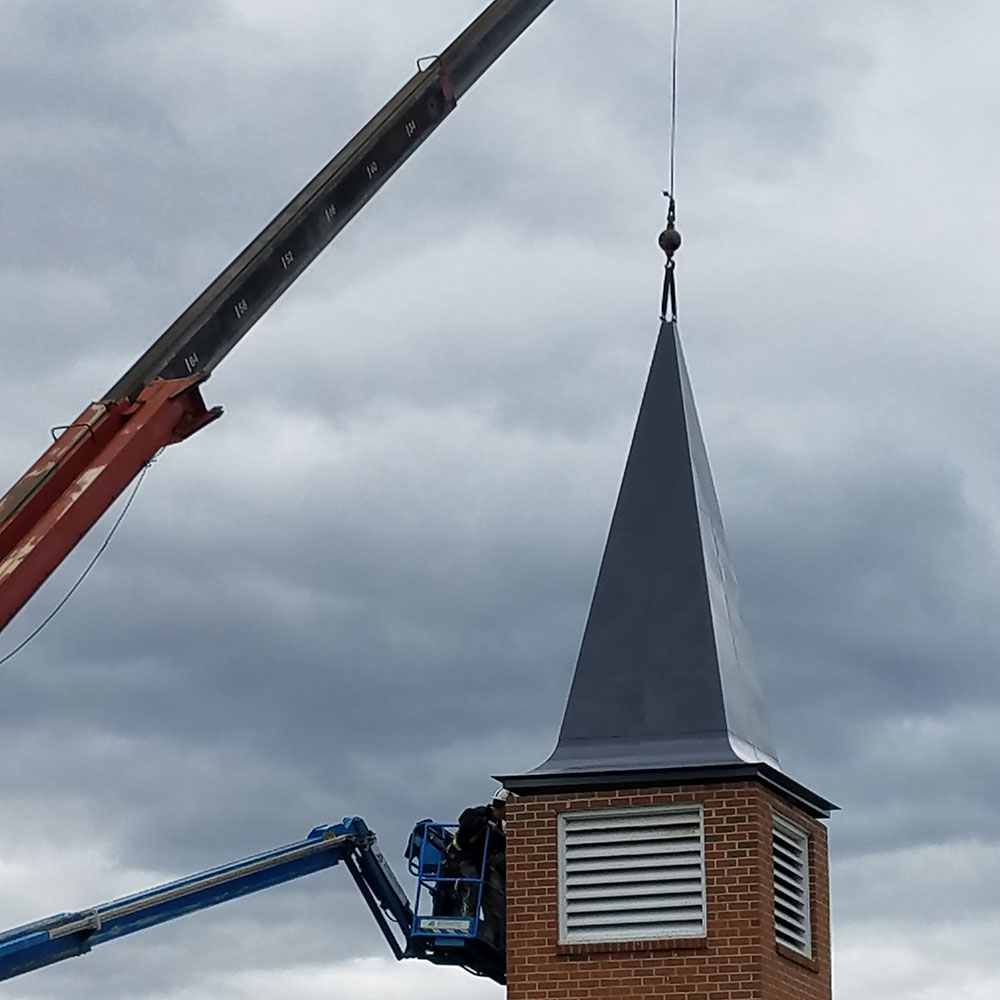 New church steeple being lifted by crane onto the bell tower